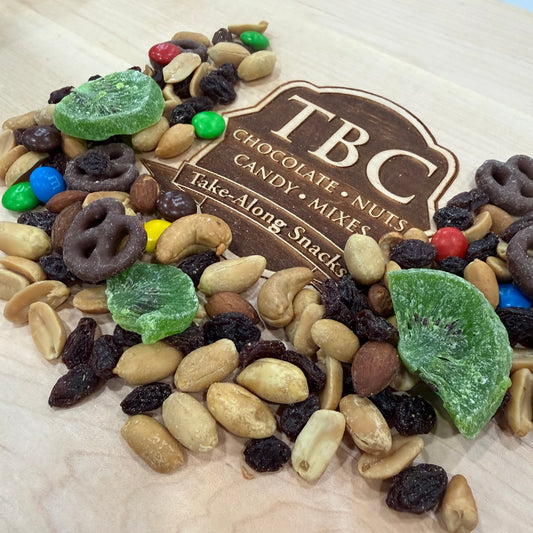 Assorted nuts, dried fruits, and candy with a TBC label on a wooden surface