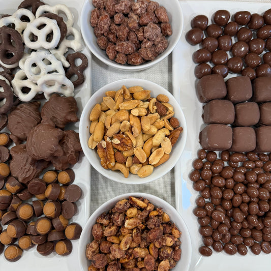 Assorted chocolate-covered treats including pretzels, nuts, and candies on a white surface.