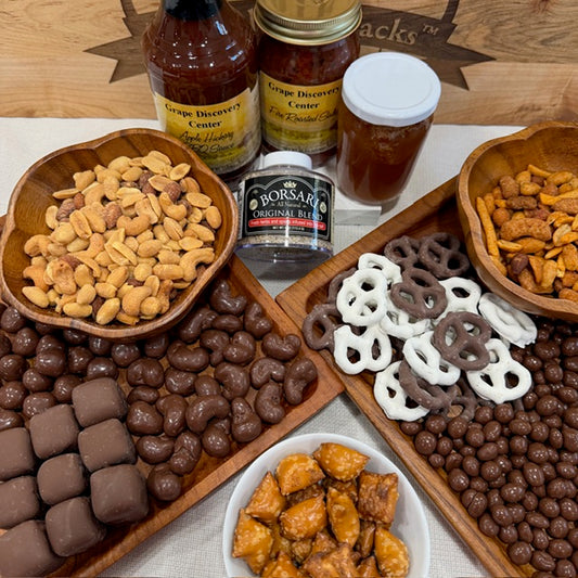 Assorted snacks including pretzels, candies, and a bottle of beer on a wooden board.