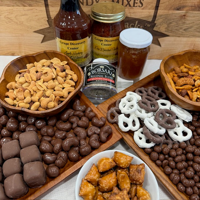 Assorted snacks including pretzels, candies, and a bottle of beer on a wooden surface.