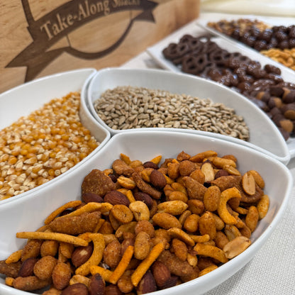 Assorted pet food mix in a white divided bowl with a wooden box labeled 'Take-Along Snacks' in the background.