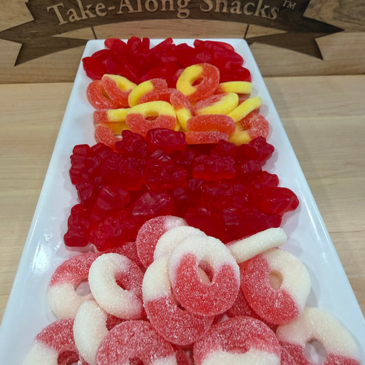 Assorted gummy candies including red, yellow, and white gummies on a white tray with 'Take-Along Snacks' branding.