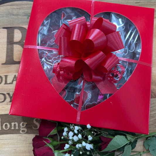 Red gift box with a large bow on a wooden surface