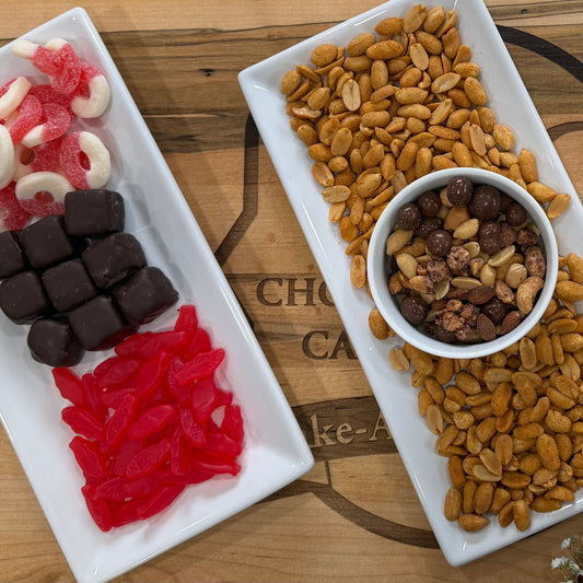 Assorted snacks including gummy bears, nuts, and chocolate-covered treats on a wooden surface.