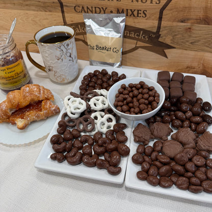Assorted chocolate-covered treats on a platter with a cup of coffee and a jar of honey.