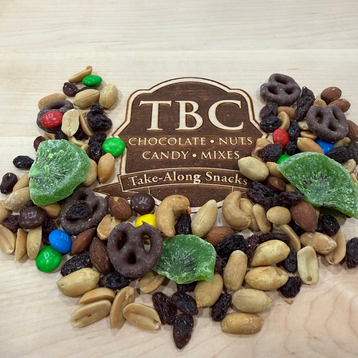 Assorted snack mix with TBC branding on a wooden surface