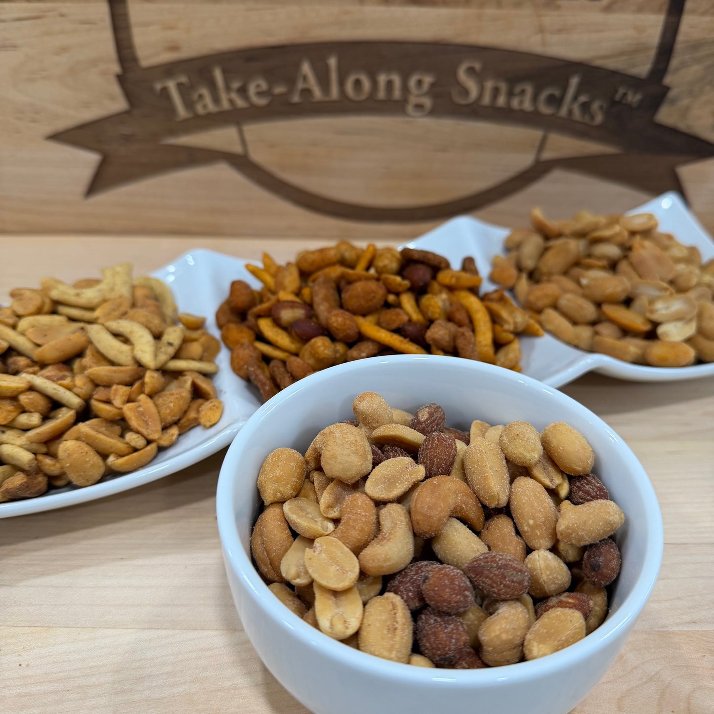 Assorted snacks in bowls with a 'Take-Along Snacks' sign in the background.