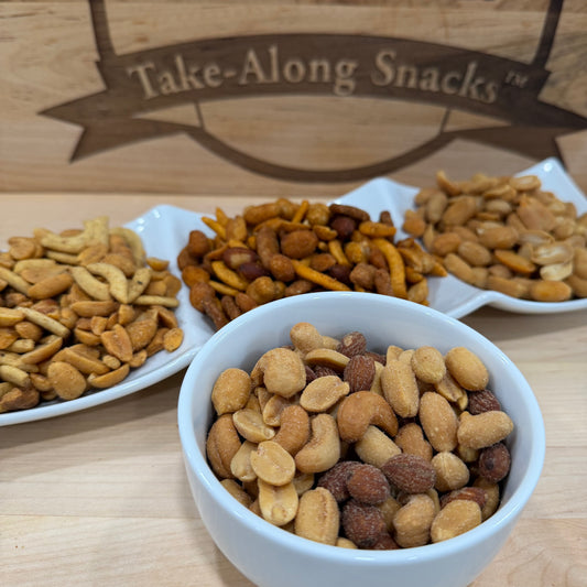 Assorted snacks in bowls with a 'Take-Along Snacks' sign in the background.