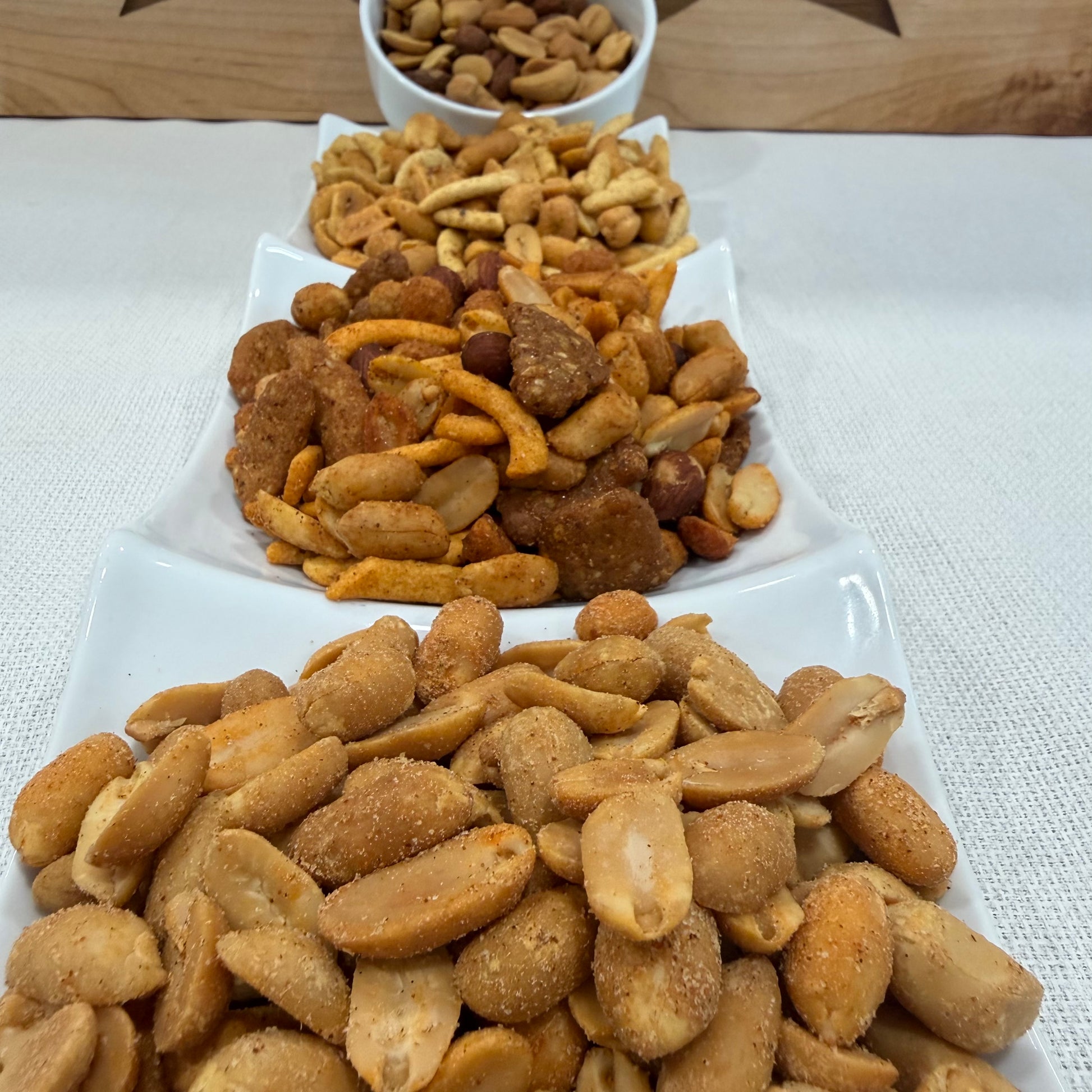 Assorted snack mix on a white plate with a wooden surface in the background