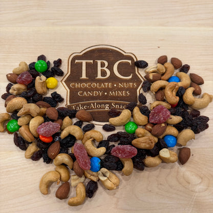 Assorted nuts and candy mix with TBC branding on a wooden surface